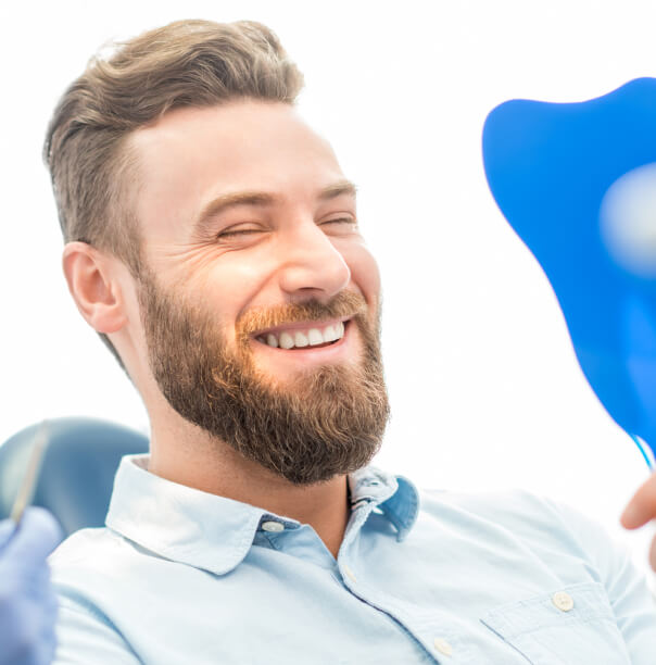 man looking at his new smile at the dentist