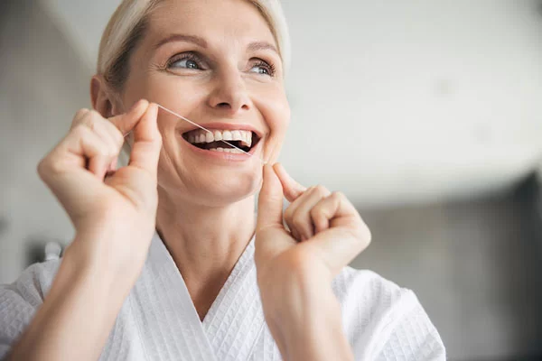 older woman flossing her teeth