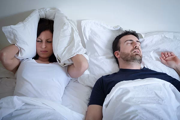 woman struggling to sleep to due her partner's loud snoring