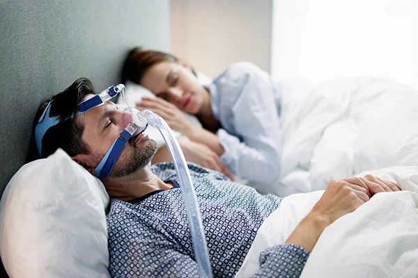 man sleeping with a sleep apnea treatment mask, a BiPAP machine