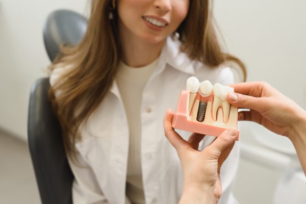 dentist showing a dental implant model to patient