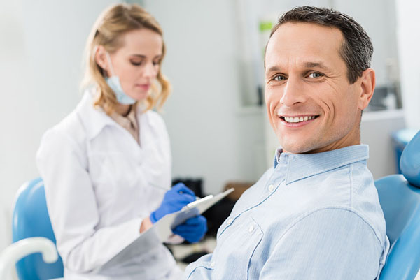 dentist taking notes while speaking to a patient