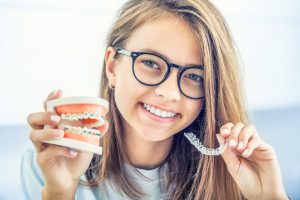 teen holding a braces and a SureSmile aligner