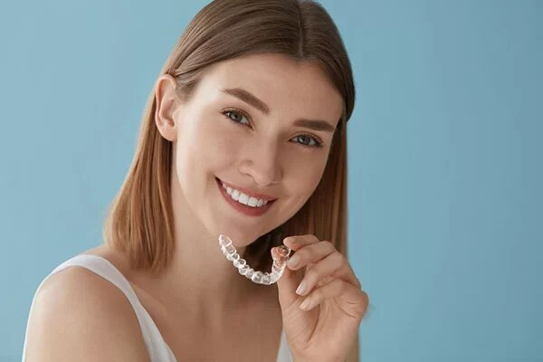 woman holding a SureSmile aligner near her smile